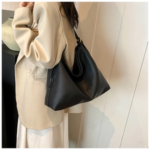 Close-up of black litchi pattern leather hobo bag worn by model in minimalist setting