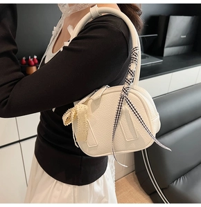 Detail of white lychee leather handbag with lace bow and checkered ribbon handle