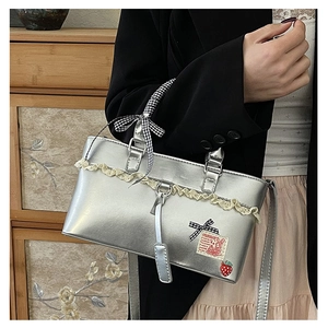 Detail of silver leather bag with lace trim, checkered bow, and cute strawberry charm