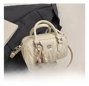 Detail of cream Boston bag featuring V-shaped quilted stitching and woven charm