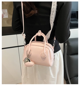 Detail of light pink oil wax leather bowling bag with heart charm and brand embossing