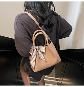 Détail du sac seau en cuir camel avec foulard en soie et bandoulière réglable