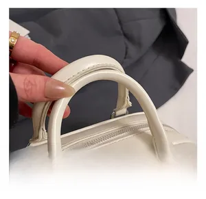 Detail showing comfortable rounded double handles and silver zipper on quilted cream handbag