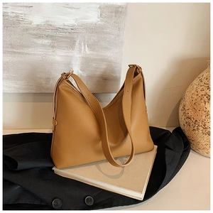 Detail of camel brown pebble leather texture on a large tote bag with gold hardware