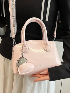 Pink patent leather handbag with glossy finish, heart pendant and crossbody strap