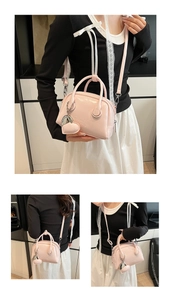 Detail view of pink glossy bowling bag showing white ribbon and heart pendant texture