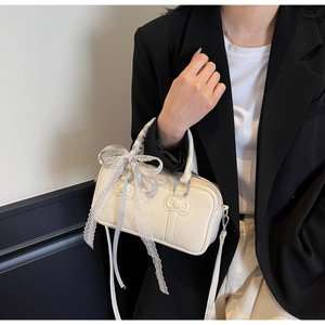 Detail of white bowling bag featuring lace bow and embossed cartoon cat pattern