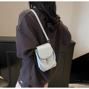 Detail of light blue-grey woven texture phone bag with metal handle and shoulder strap