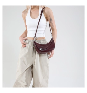Détail du sac demi-lune bordeaux avec finition huilée brillante et boucles argentées