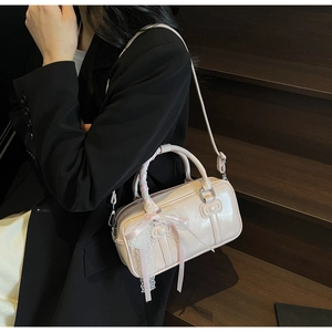 Detailed view of the light pink bow-embossed handbag with lace charm and silk handle wrap