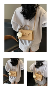 Dettaglio borsa a mano quadrata in pelle kaki con ciondolo in peluche di alpaca bianco