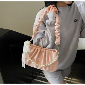 Close-up of pink ruched underarm bag with pearl chain strap and lace bow detail