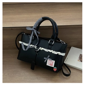 Close-up of black PU leather bag featuring lace trim, plaid ribbon bow, and rabbit patch