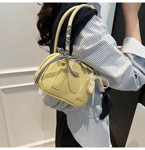 Detail of yellow lychee texture leather handbag with gingham bow and lace trim