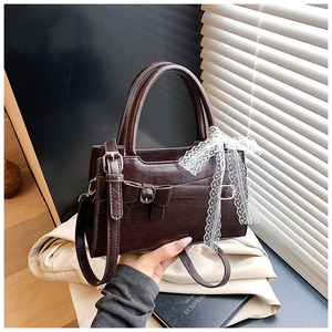 Dettaglio di borsa vintage marrone scuro con fiocco e decorazione con sciarpa in pizzo