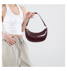 Détail du sac demi-lune en cuir ciré bordeaux avec fermeture éclair argentée brillante