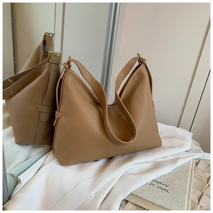 Close-up of khaki pebbled leather tote bag with adjustable strap and gold metal buckle
