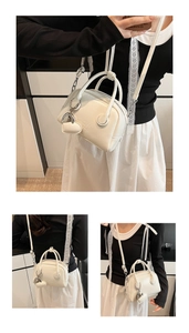 Detailed view of cream PU leather bowling bag with heart charm and embossed lettering