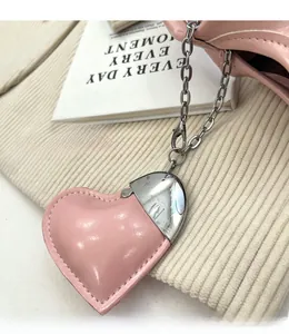 Gros plan du charm de sac en cuir rose en forme de cœur avec chaîne argentée