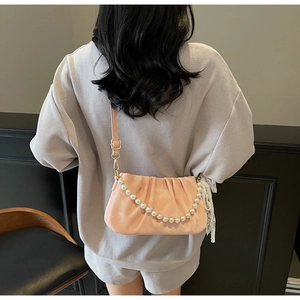 Detail of pink ruched shoulder bag with luxury large pearl chain and smooth texture