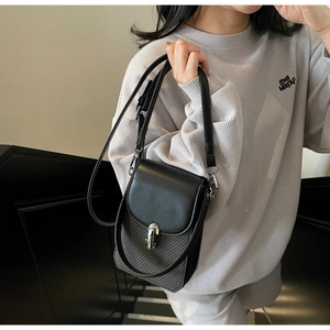 Detail of black crossbody phone bag with silver metal clasp and woven texture panel
