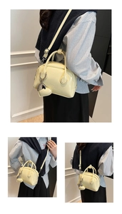Detail of light yellow bowling bag featuring metal heart charm and embossed texture