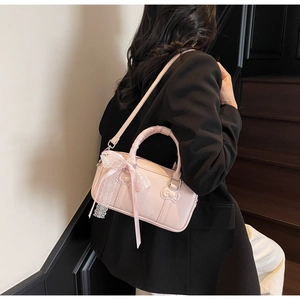 Detail of pink leather handbag showing lace bow accents and a textured ribbon relief