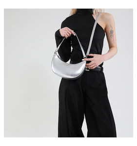 Détail du sac demi-lune argenté en cuir huilé brillant avec des coutures précises