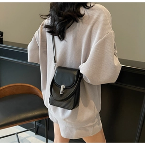 Detail view of black crossbody phone bag with woven texture and silver metal buckle