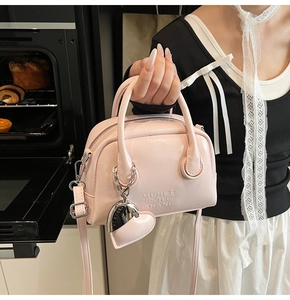 Close-up of pink mini Boston bag with heart charm and MUHETI SHI SHANG embossing