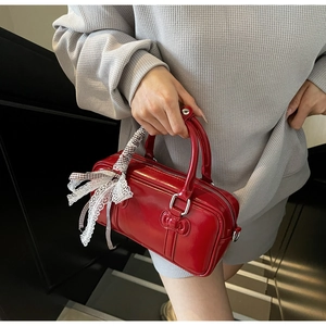 Detail of red patent leather Boston handbag with lace scarf and metal hardware