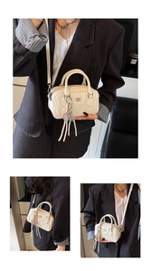 Detail of creamy white quilted Boston bag with tassel charm and chain shoulder strap