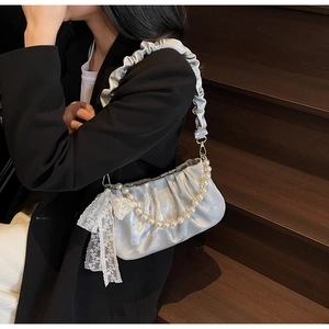 Detail of silver pleated satin handbag with white lace bow and pearl beaded strap