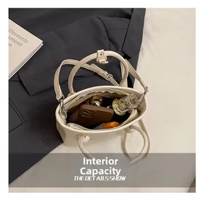 Internal capacity of minimalist off-white leather bucket bag showing daily essentials