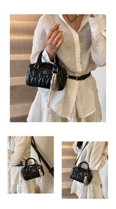 Detail of black quilted leather handbag with wavy stitching and brand logo texture