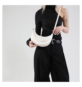 Sac bandoulière demi-lune blanc cassé porté par un mannequin en tenue minimaliste