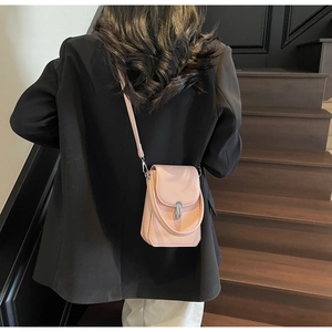 Pink woven leather crossbody bag with silver buckle worn on a black blazer jacket