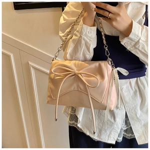 Detail view of pink ballet-style shoulder bag featuring a large bow and silver chain strap