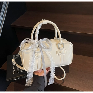Detail of cream white bowling bag with lace bows and ribbon wrapped handle on wood