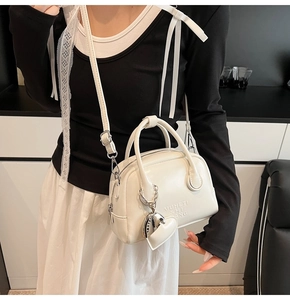 Detail of white glossy bowling bag with embossed lettering and heart charm on model