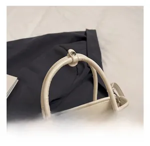 Detail view of the cream bucket bag handle with spherical accents and silver snap button