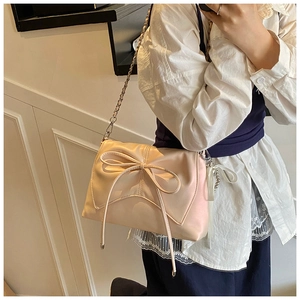 Close-up of the elegant bow detail and soft pleated texture on the pink underarm bag
