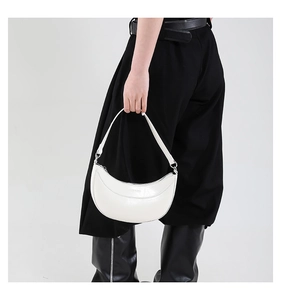 Détail du sac demi-lune blanc avec une finition lisse et des accents en métal argenté
