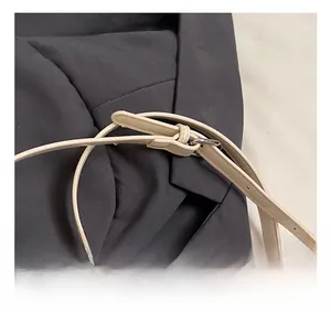 Detail showing adjustable beige leather shoulder strap with silver metal buckle on bucket bag
