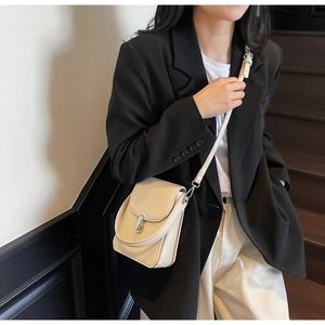 Detail of minimalist cream crossbody bag with silver buckle and woven texture flap