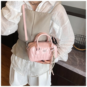Detailed close-up of a pink quilted crossbody bag with metal zipper and tassel detail