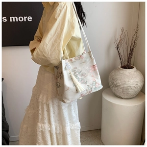 Détail du sac cabas floral avec motifs chinois et décoration élégante de franges latérales