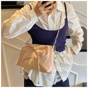 Close-up of beige ballet style bow shoulder bag with chain strap and ribbon detail