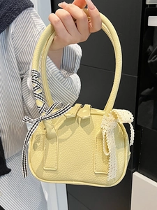 Yellow leather bowling bag with lace bow and plaid ribbon shown held by a model