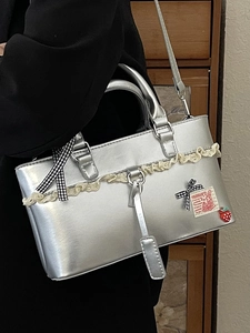 Silver metallic crossbody bag with lace ruffles, bow, and strawberry charm decoration